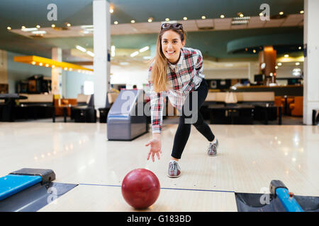 Woman throwing bowling ball in club Stock Photo