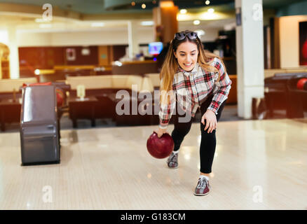 Woman throwing bowling ball in club Stock Photo