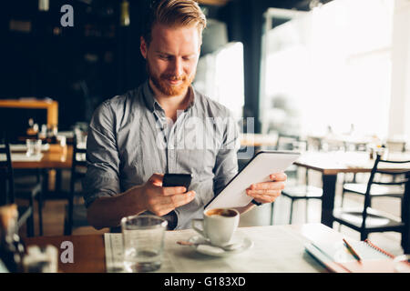 Busy blogger multitasking in cafe