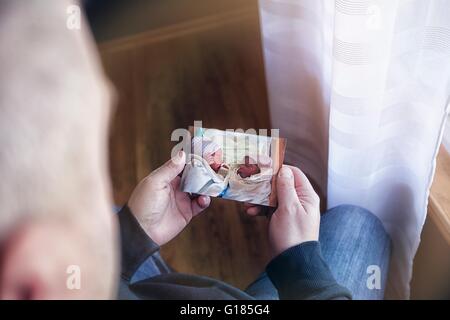 Over shoulder view of father holding photograph of baby twins Stock Photo