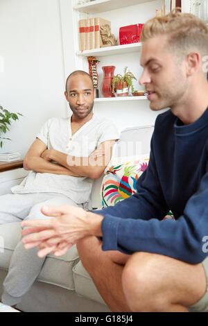 Homosexual couple sitting on sofa having disagreement Stock Photo