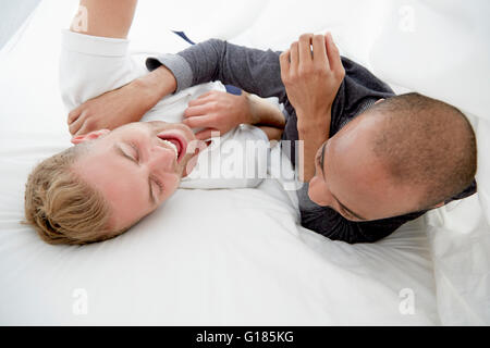 Homosexual couple fooling around on bed laughing Stock Photo