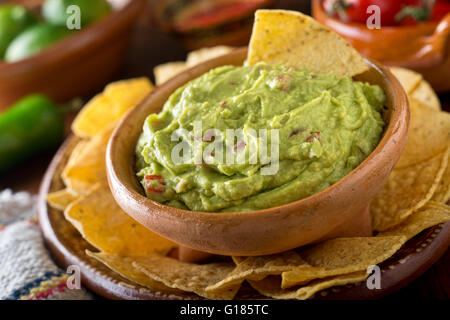 A delicious authentic mexican guacamole dip with avocado, lime, and tomato. Stock Photo