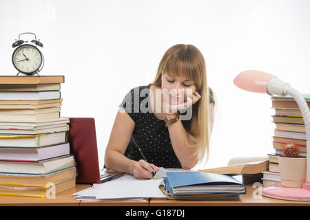 college student smiling engaged at the table cluttered with books in the library Stock Photo