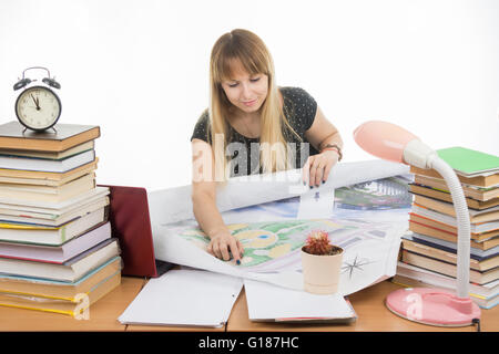 Girl student studying design drawing master plan at a table cluttered with books Stock Photo
