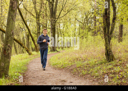 Young sporty man jogging in the morning forest. Trail runner in spring outdoors Stock Photo