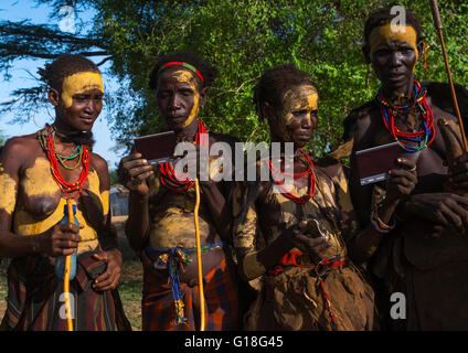 Dassanech tribe women looking polaroid pictures of themselves, Omo valley, Omorate, Ethiopia Stock Photo