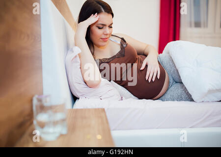 Beautiful pregnant woman struggling with headache and resting