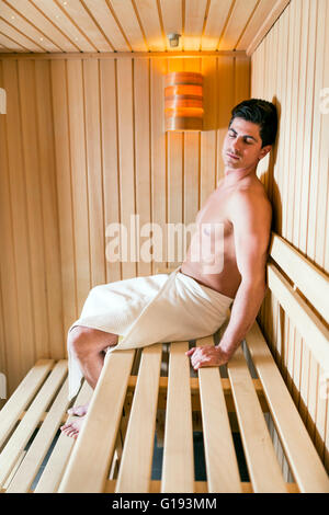 Handsome man relaxing in a sauna with towel wrapped around his waist Stock Photo