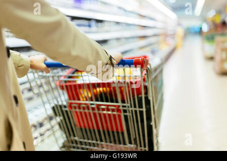 Woman pushing shopping trolley in supermarket Stock Photo