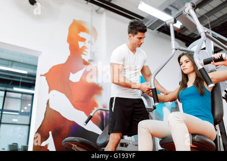 Beautiful woman exercising in gym with some help by personal trainer Stock Photo