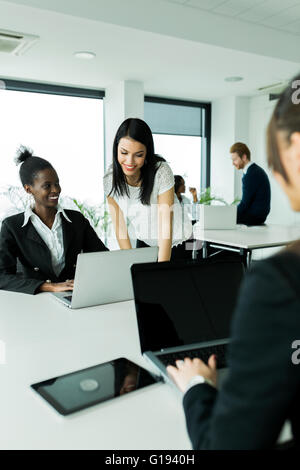 Black and white businesswomen looking at a laptop and working in a neat office environment Stock Photo