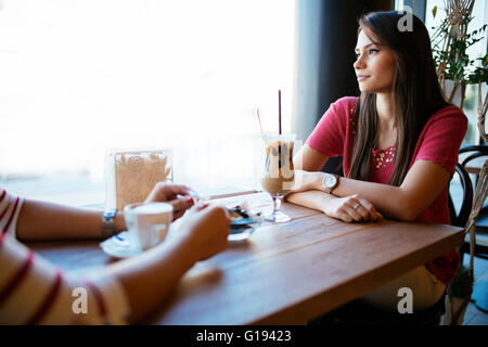 Beautiful woman talking to friend in restaurant while drinking coffee Stock Photo