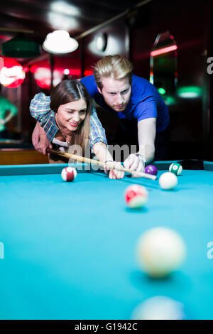 Young handsome man and woman flirting while playing billiard Stock Photo