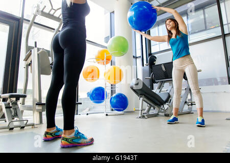 Women, friends training in gym and stretching muscles with medicine ball Stock Photo