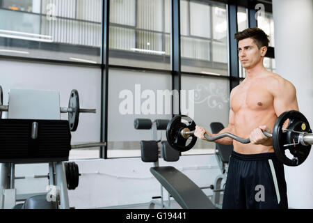 Muscular man bodybuilding in gym, lifting weights Stock Photo