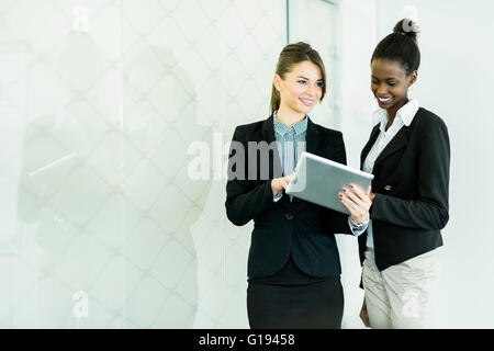Two businesswomen looking at a tablet and discussing results with a glass reflection Stock Photo