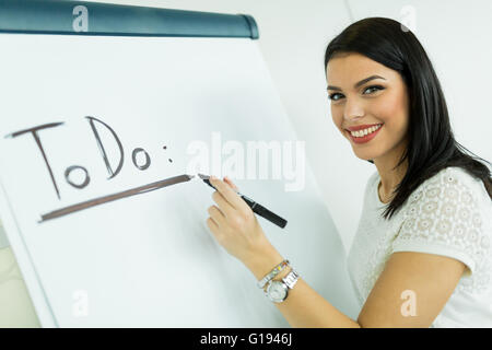 Beautiful, young, businesswoman writing todo onto a white writing board