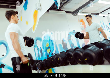 Handsome man lifting weights in gym and staying fit Stock Photo