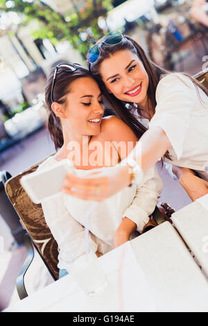 Two young beautiful women taking a selfie of themselves during lunch break Stock Photo
