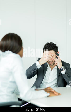 Businessman receiving bad news on the phone having a headache over the problems Stock Photo