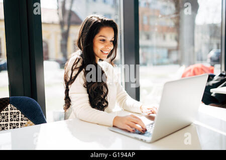 Beautiful brunette using laptop in cafe Stock Photo