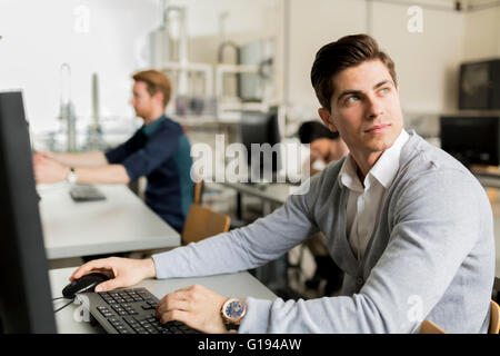 Young handsome student using computer in classroom Stock Photo