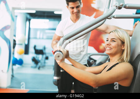 Beautiful woman exercising in gym with some help by personal trainer Stock Photo