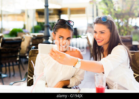 Two young beautiful women taking a selfie of themselves during lunch break Stock Photo