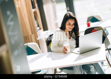 Beautiful brunette enjoying coffee and using laptop Stock Photo