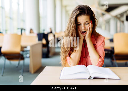 Female student studying and reading in a library but is having a hard time understanding the material Stock Photo