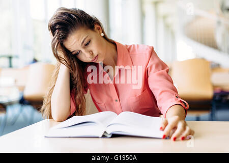 Female student studying and reading in a library but is having a hard time understanding the material Stock Photo