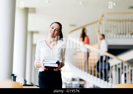 Beautiful woman holding books and smiling in a modern library Stock Photo