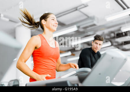 Beautiful young woman running on a treadmill in gym and smiling Stock Photo