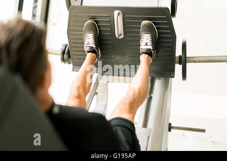 Young male working out in a gym and doing leg exercises Stock Photo