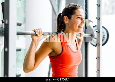 Focused young beautiful woman lifting weights in a gym Stock Photo
