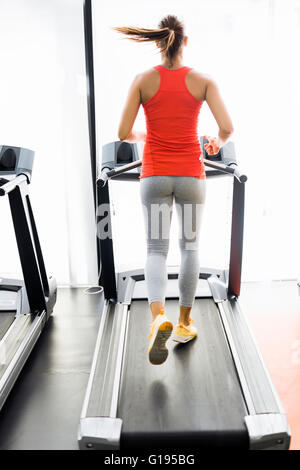 Beautiful young woman running on a treadmill in fitness center Stock Photo
