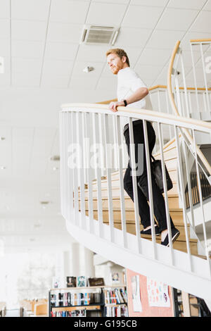 Handsome businessman walking down the stairs whilst holding a bag Stock Photo