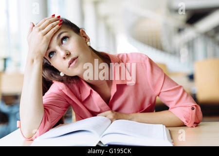 Female student studying and reading in a library but is having a hard time understanding the material Stock Photo