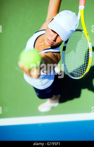 Beautiful female tennis player serving outdoor and a closeup of the serve from above Stock Photo