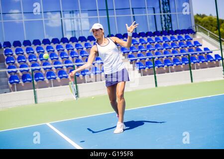 Beautiful female tennis player in action, hitting a forehand Stock Photo