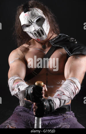 Costumed hero as a street maniac with a bat. Casey Jones on black background. Stock Photo