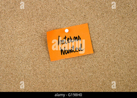 Interns Wanted written on orange paper note pinned on cork board with white thumbtacks, copy space available Stock Photo