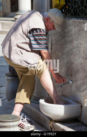 Muslim man washing his feet at the New Mosque, Eminonu Yeni Camii, Eminonu, Istanbul, Turkey Stock Photo