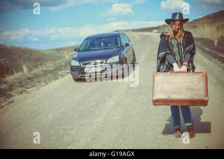 girl with a suitcase on the road Stock Photo