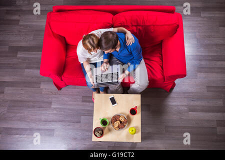 Young couple using laptop while sitting on couch Stock Photo