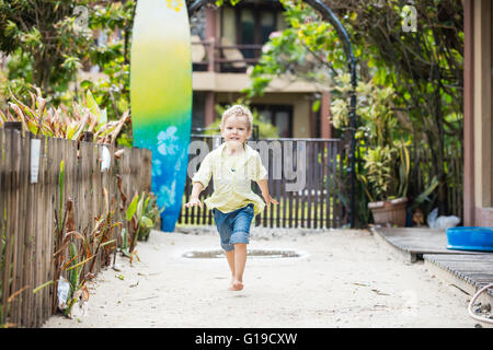 Cute blonde boy walking barefoot in tropical resort Stock Photo