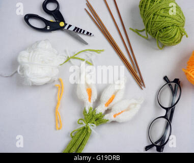 Romantic desk with ornament from handmade product, lily flower knit from yarn, knitting pencil, glasses, beautifil craft Stock Photo