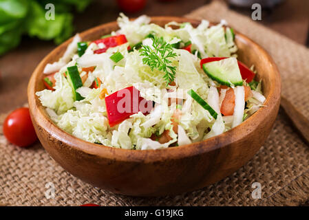 Vegetarian vegetable salad (cabbage, tomato, paprika, cucumber, onion) in a wooden bowl Stock Photo
