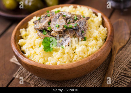 Millet porridge with mushrooms in a wooden bowl Stock Photo